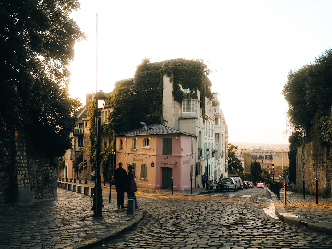 Cobblestone street with buildings and people at sunset.